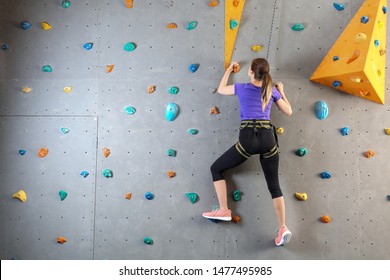 Young Woman Climbing Wall In Gym