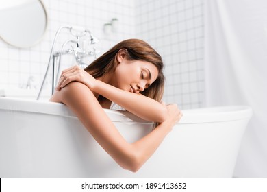 young woman with closed eyes taking bath at home