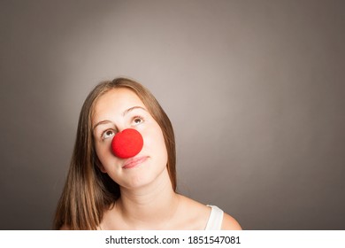 Young Woman With Clown Nose On A Grey Background