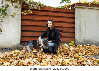 young woman in a coat with a dog on a walk near the house