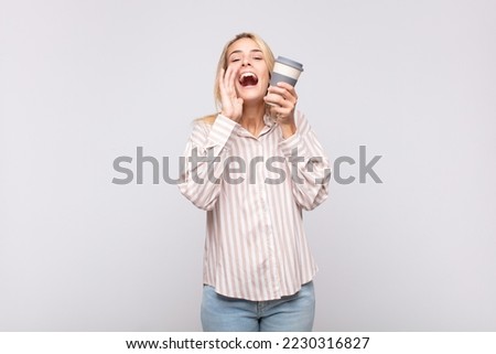 young woman with a coffee feeling happy, excited and positive, giving a big shout out with hands next to mouth, calling out