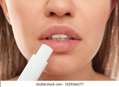 Young Woman With Cold Sore Applying Lip Balm, Closeup