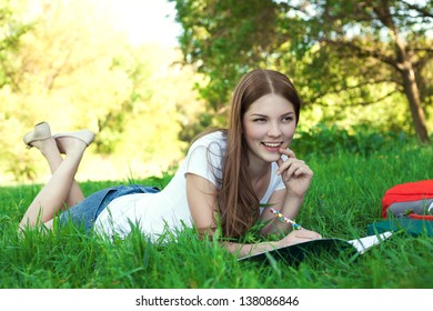 Young Woman College Student With Book And Bag Studing In A Park