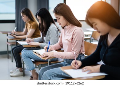 Young woman college students sitting on lecture chair in classroom studying, writing on examination paper answer sheet in doing the final examination test. College students in the classroom