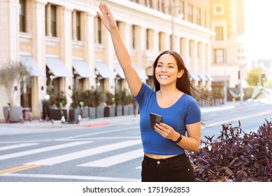 Young woman of color waves her hand to call a ride share in the City - Uber - Lyft - Daytime - Powered by Shutterstock