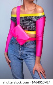 Young Woman Colorful Long Sleeve Top And Magenta Fanny Pack, 80s Fashion Look With High Waist Ripped Jeans, Pink Belt Bag