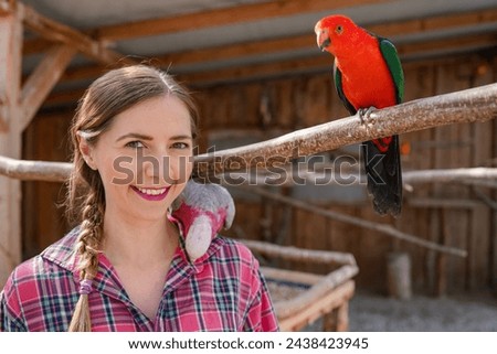 Young woman with colourful parrot birds around, one sitting on her shoulder