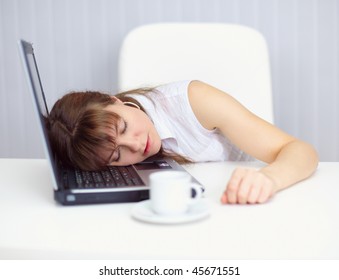 Young woman comically asleep on the keyboard at the table