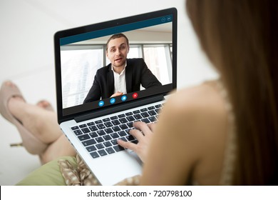 Young woman communicating with man in formal suit via video call application. Dressy couple chatting. Long distance relationship, virtual communication. Close up view over shoulder, focus on screen.