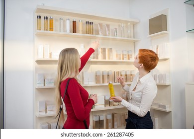 Young Woman Comparing Cosmetics With Saleswoman In A Cosmetics Shop