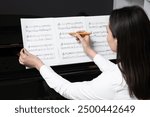 Young woman composing music on black piano