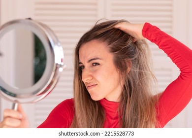 Young Woman Concern About Her Hair Loss In Autumn Time While Looking To Round Hand Mirror In Red Outfit