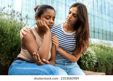 Young woman consoling and comforting upset and depressed African American female friend in park outdoors. - Powered by Shutterstock