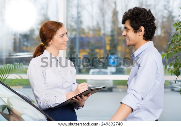 Young\
woman consultant in show room talking with\
client