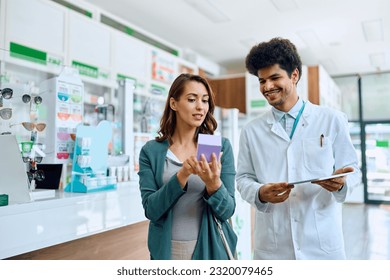 Young woman consulting with her pharmacist while choosing vitamins in a pharmacy.  - Powered by Shutterstock