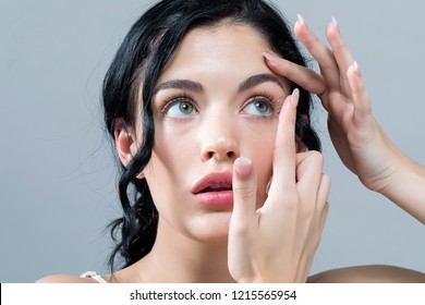 Young woman with contact lenses on a gray background