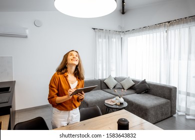 Young woman controlling home light with a digital tablet in the living room. Concept of a smart home and light control with mobile devices