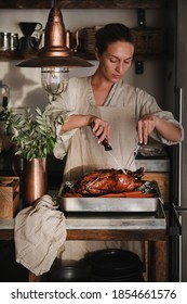 Young Woman Cooking And Carving Whole Oven Roasted Duck For Thanksgiving Holiday Or Christmas Party Celebration In Kitchen Interior. Traditional Autumn Or Winter Holiday Comfort Food For Gathering