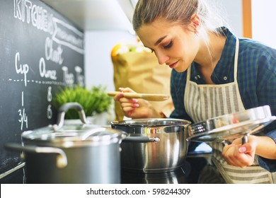 Young Woman Cooking In Her Kitchen Standing Near Stove