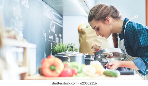 Young Woman Cooking In Her Kitchen Standing Near Stove