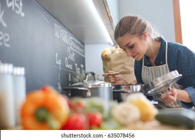 Young Woman Cooking In Her Kitchen Standing Near Stove