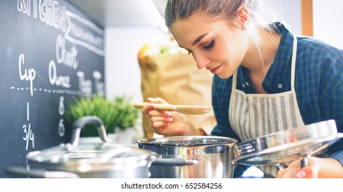 Young woman cooking in her kitchen standing near stove
