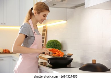 Young Woman Cooking On Stove In Kitchen