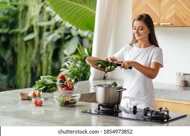 Young woman cooking in the open kitchen. Healthy Food. Dieting Concept. Healthy Lifestyle. Cooking At Home. Prepare Food