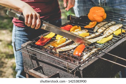 Young Woman Cooking Organic Vegetables At Barbecue Dinner Outdoor - Couple Grilling Peppers And Aubergines For Vegan Bbq - Vegetarian And Healthy Lifestyle Concept - Focus On Left Girl Hand