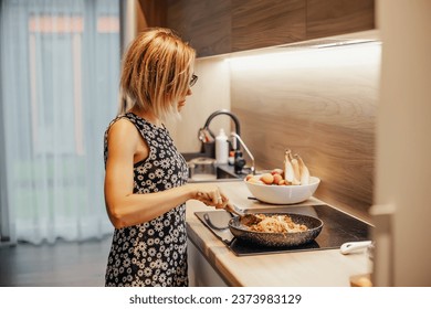 Young woman cooking vegetables in a pan. Cooking at home concept. - Powered by Shutterstock