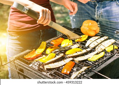 Young Woman Cooking Vegetables For Vegetarian Barbecue Dinner Outdoor - Couple Grilling Peppers And Aubergines For Bbq - Vegan And Healthy Lifestyle Concept - Focus On Barbecue Tongs