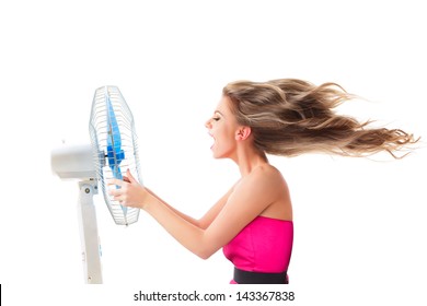 Young Woman Cooling Face Under Wind Of Cooler Fan Isolated On White Background