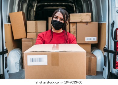 Young Woman Courier Delivering Package From Van During Delivery Round To Customer - Pov Parcel Pick-up During The Global Coronavirus Covid-19 Pandemic - People Wearing Protective Face Masks And Smile