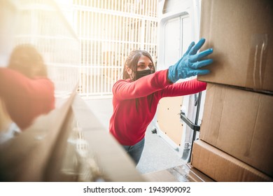 Young Woman Courier Loads Package From Hes Delivery Van Wearing Face Mask And Gloves During Global Coronavirus Covid-19 Pandemic - Concept Of Fast And Safe Shipping