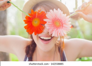 Young woman covering her eyes with fresh colorful flowers. Enjoying spring time