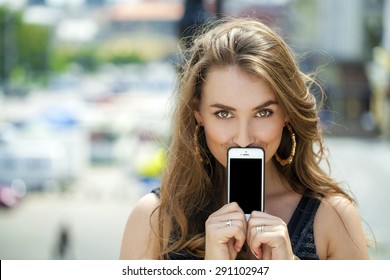 Young Woman Covers Her Face Screen Smartphone On A Background Summer Street