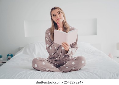 Young woman in cozy pajamas sitting on a comfortable bed enjoying morning light at home, expressing calmness - Powered by Shutterstock