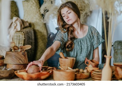 Young woman crafter holding handmade wooden cup in her workshop with eco natural tableware. Woodcraft local small business concept. Selective focus.