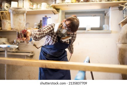 Young Woman Craftswoman Applying Varnish On Wooden Elements In Woodshop