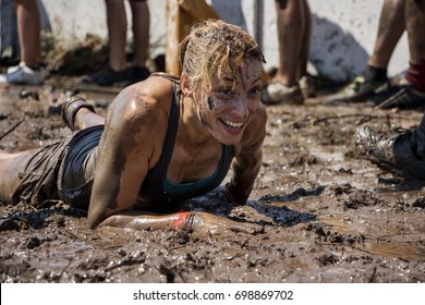 Young Woman Crawling In The Mud; Participation In Extreme Sport, Physical Strength Challenge