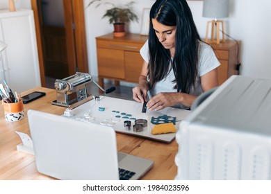 Young woman creating handmade jewelry using clay and working from home. - Powered by Shutterstock