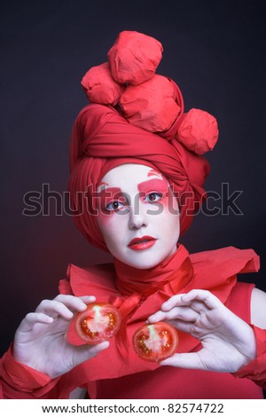 Young woman in creative image and with tomato on her hands.