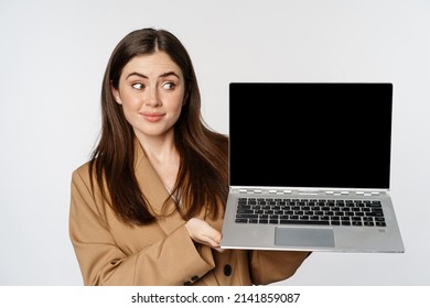 Young Woman Cringe And Look Skeptical, Showing Laptop Screen, Standing Over White Background