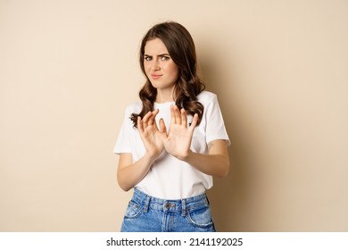 Young Woman Cringe, Shaking Hands To Decline, Reject Disgusting Bad Offer, Standing Over Beige Background