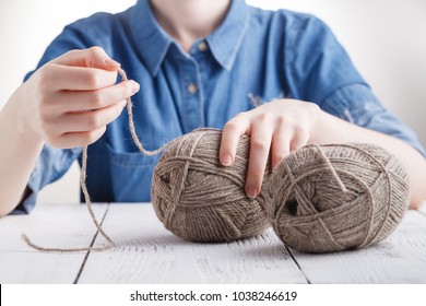 Young Woman Crochets A Warm Blanket With Beige Wool