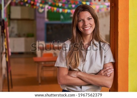 Young woman with crossed arms as a self-confident educator in preschool or daycare