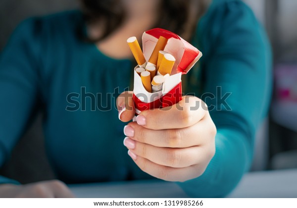 若い女性はタバコの箱を押しつぶす の写真素材 今すぐ編集