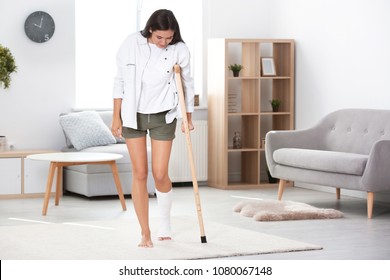 Young Woman With Crutch And Broken Leg In Cast At Home