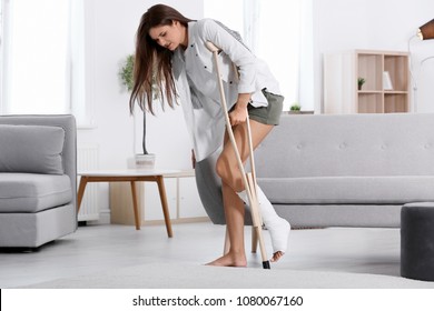 Young Woman With Crutch And Broken Leg In Cast At Home