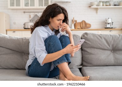 Young Woman Cry Reading Bad News Email, Break Up Message From Ex-boyfriend On Smartphone Sitting Lonely On Couch In Living Room. Depressed Unhappy Female Desperate Of Heartbreak Sms On Mobile Phone